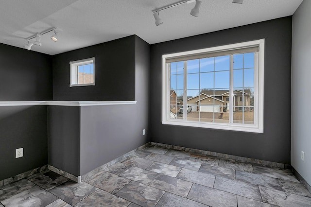 unfurnished room with a textured ceiling and baseboards