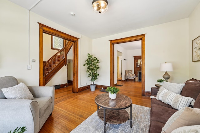 living area with stairs, wood finished floors, and baseboards