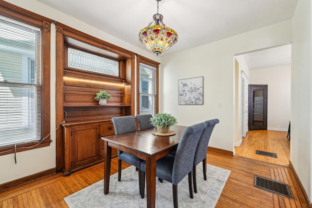 dining space featuring light wood finished floors, plenty of natural light, and baseboards