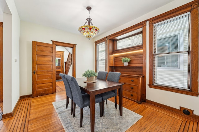 dining space with stairway, baseboards, and light wood-type flooring