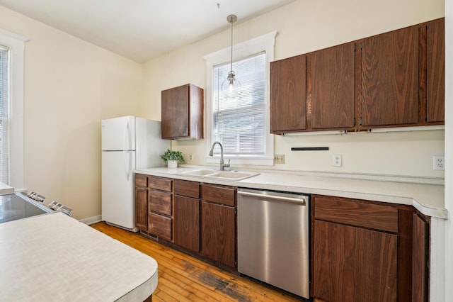 kitchen with dishwasher, a sink, freestanding refrigerator, light wood finished floors, and light countertops