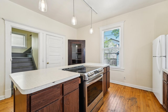 kitchen with stainless steel range with electric stovetop, light countertops, light wood-type flooring, baseboards, and pendant lighting