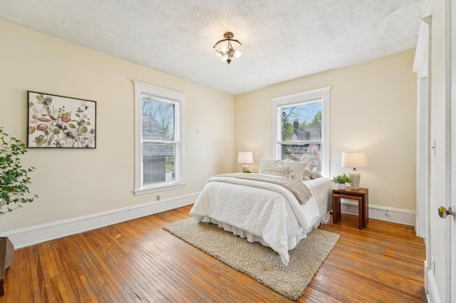 bedroom featuring baseboards, hardwood / wood-style floors, and a textured ceiling