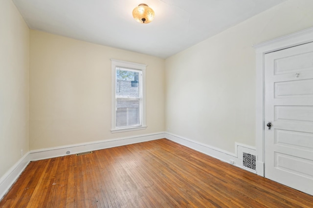 empty room with wood-type flooring and baseboards