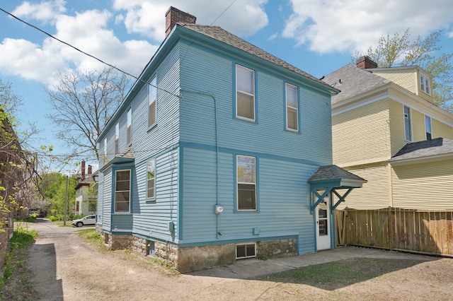 back of house featuring fence and a chimney