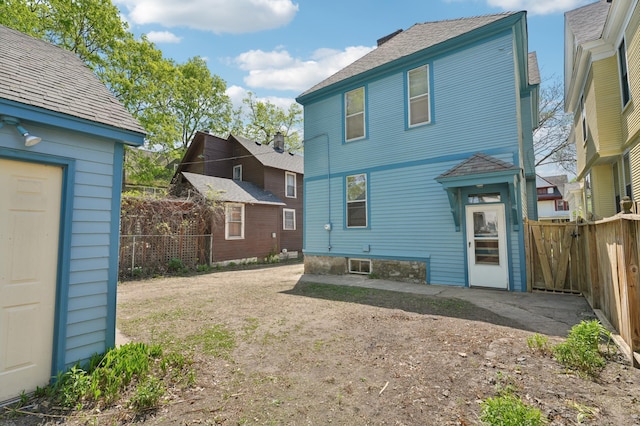 back of property featuring fence and a shingled roof