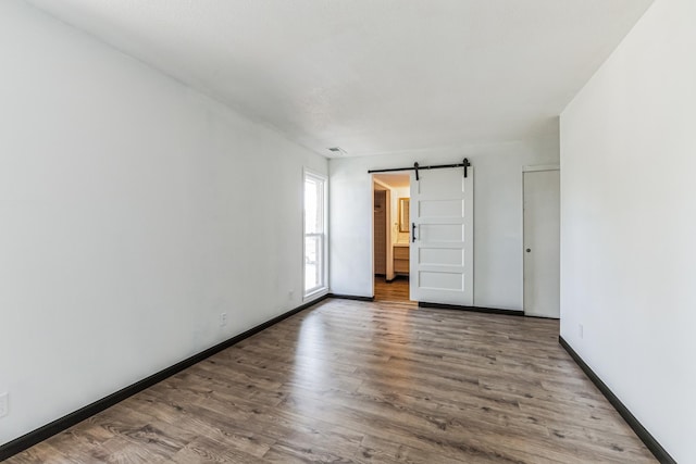 6417 Colony Way Unit 2A, Edina, MN 55435 - spare room featuring a barn door, wood finished floors, baseboards, and visible vents