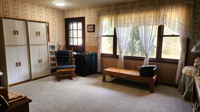 sitting room featuring wallpapered walls, carpet, visible vents, and a textured ceiling