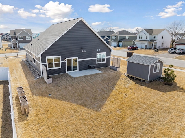 rear view of house featuring a storage unit, an outbuilding, fence, a residential view, and a patio area