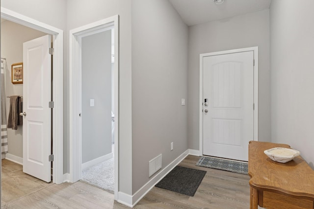 foyer entrance featuring visible vents, baseboards, and light wood-style flooring