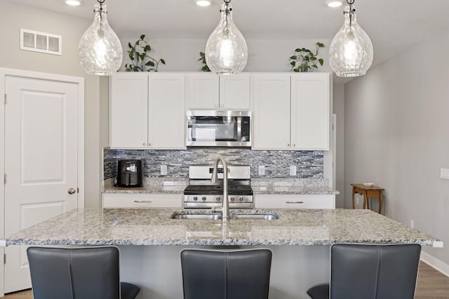 kitchen with visible vents, white cabinets, appliances with stainless steel finishes, and decorative backsplash