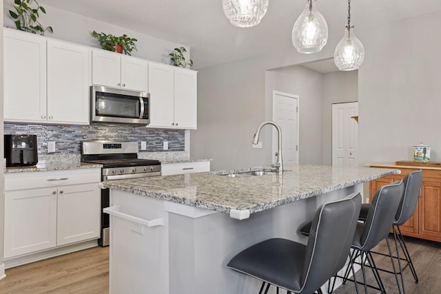 kitchen with decorative backsplash, light wood-style flooring, stainless steel appliances, and a sink