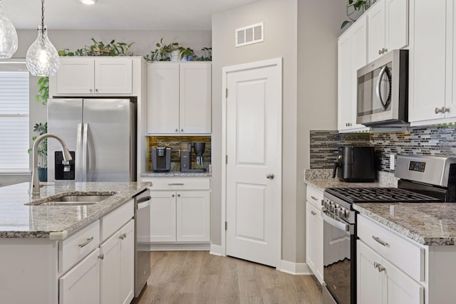 kitchen with visible vents, a sink, appliances with stainless steel finishes, white cabinets, and light wood finished floors