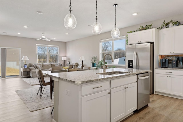 kitchen with a sink, plenty of natural light, appliances with stainless steel finishes, and a center island with sink