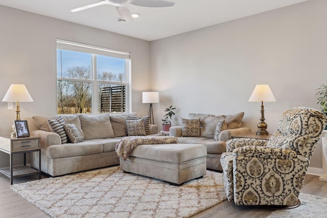 living room featuring baseboards, ceiling fan, and wood finished floors