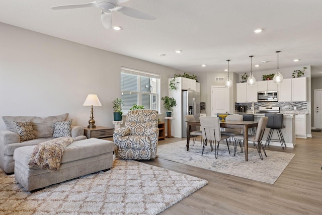 living room featuring visible vents, recessed lighting, a ceiling fan, and light wood-style floors