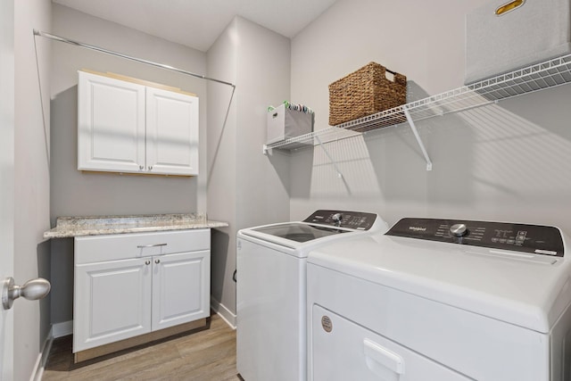 laundry area featuring baseboards, cabinet space, light wood-type flooring, and washer and clothes dryer