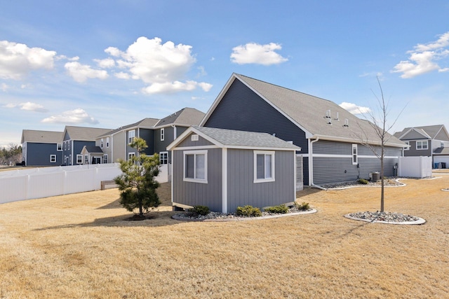 view of side of property featuring an outbuilding, a residential view, a yard, and fence