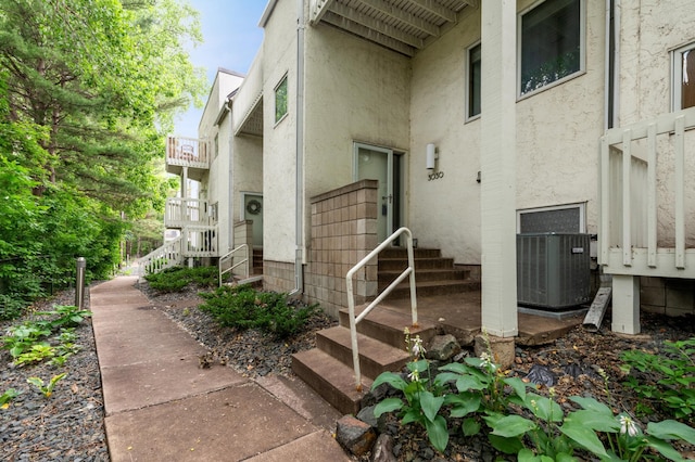 property entrance featuring central air condition unit and stucco siding