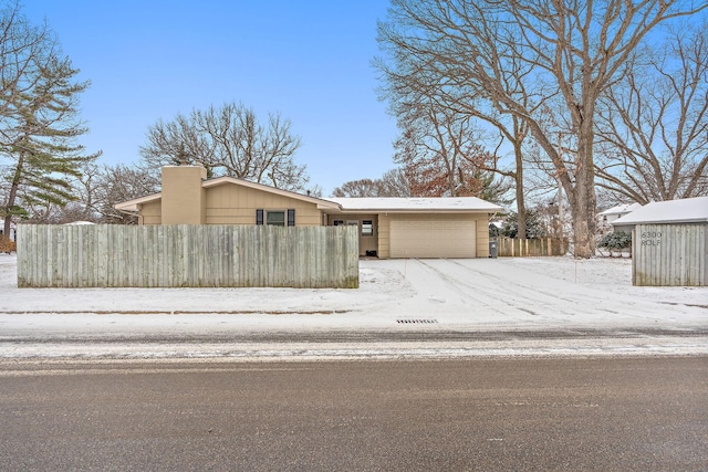 view of front facade with a garage, a fenced front yard, and a chimney