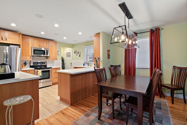 kitchen featuring an inviting chandelier, light wood-style flooring, a peninsula, and stainless steel appliances