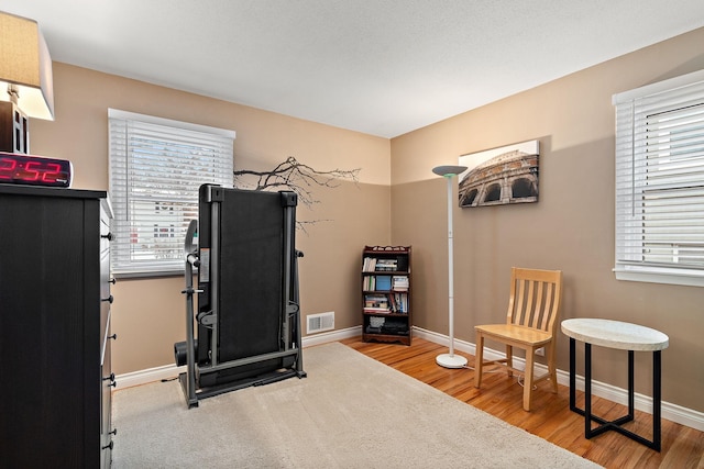 exercise area featuring wood finished floors, baseboards, and visible vents