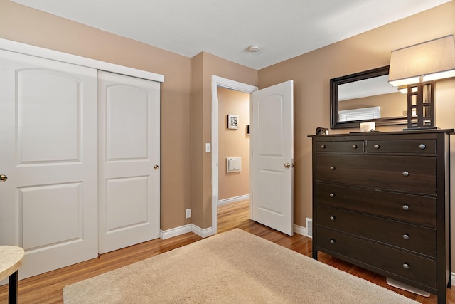 bedroom featuring a closet, baseboards, and light wood finished floors