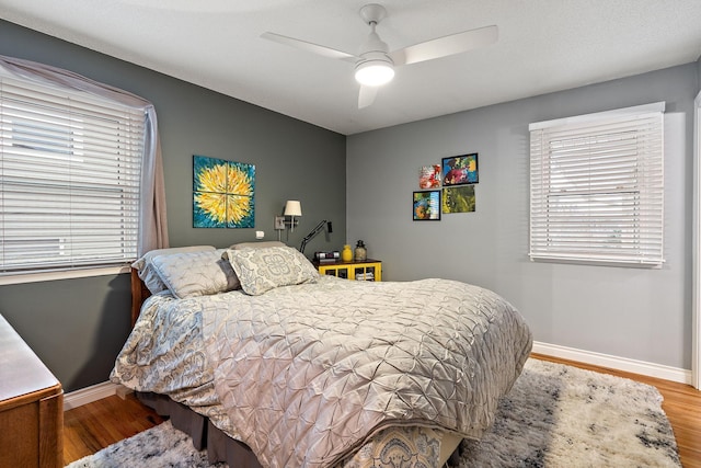 bedroom with a ceiling fan, baseboards, and wood finished floors