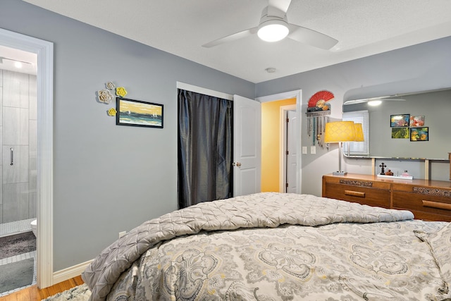 bedroom with ceiling fan, baseboards, ensuite bath, and wood finished floors