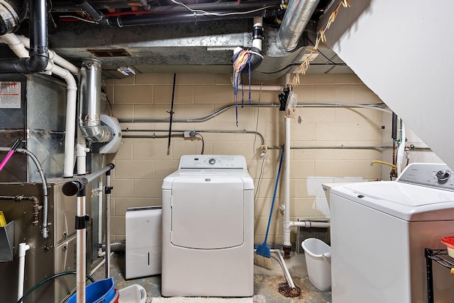 washroom featuring washing machine and clothes dryer, laundry area, and heating unit