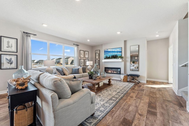 living area with recessed lighting, a textured ceiling, baseboards, and wood finished floors