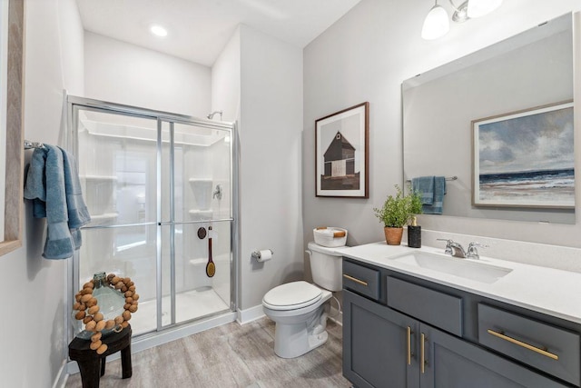 full bathroom featuring vanity, toilet, wood finished floors, and a stall shower