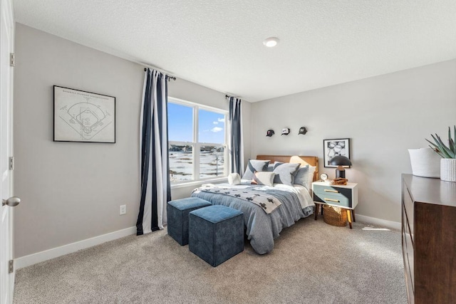 bedroom featuring baseboards, light colored carpet, and a textured ceiling