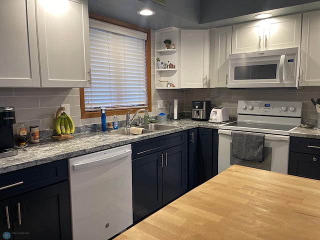 kitchen with a sink, white appliances, tasteful backsplash, and wooden counters