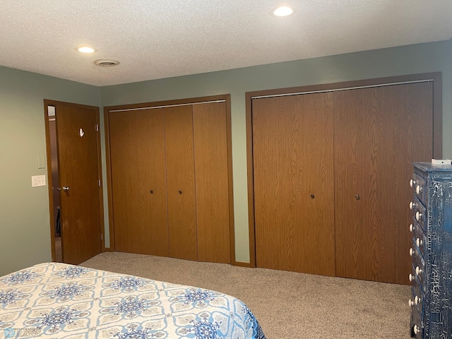 carpeted bedroom with recessed lighting, two closets, and a textured ceiling