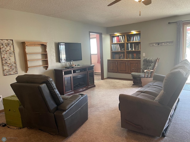 living area featuring built in features, carpet, baseboards, ceiling fan, and a textured ceiling