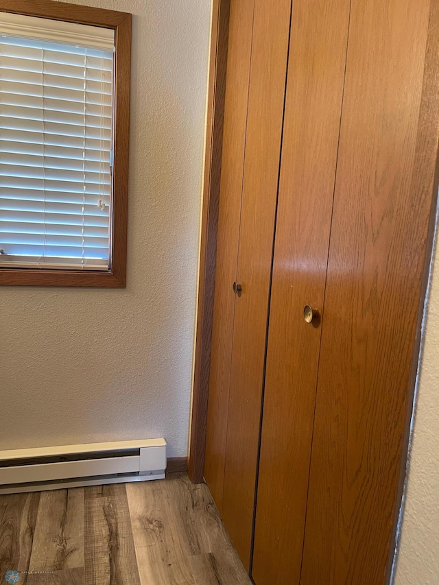 room details with wood finished floors, baseboards, a textured wall, and a baseboard radiator