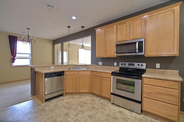 kitchen with a sink, appliances with stainless steel finishes, a peninsula, and light countertops