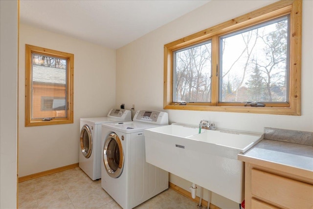 clothes washing area featuring washer and dryer, baseboards, laundry area, and a sink