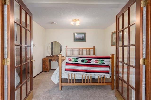 bedroom featuring french doors, visible vents, carpet floors, and a textured ceiling