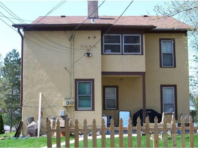 2309 Buchanan St NE, Minneapolis, MN 55418 - back of house featuring a fenced front yard, stucco siding, and a shingled roof
