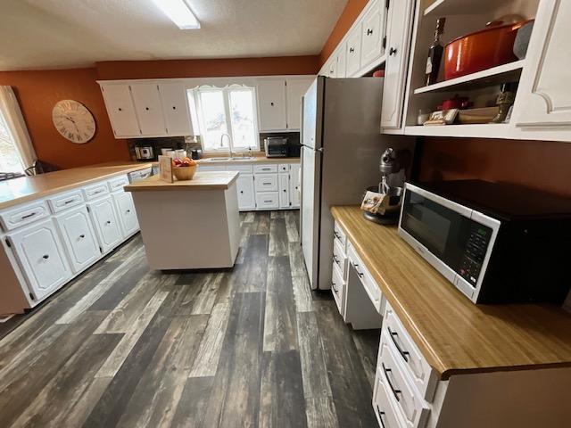 kitchen with a kitchen island, white cabinets, and butcher block counters