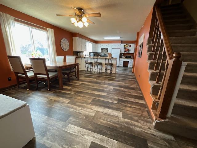 dining room with stairway, dark wood finished floors, and a ceiling fan