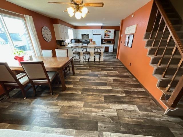 dining space with dark wood-style floors, stairway, and ceiling fan