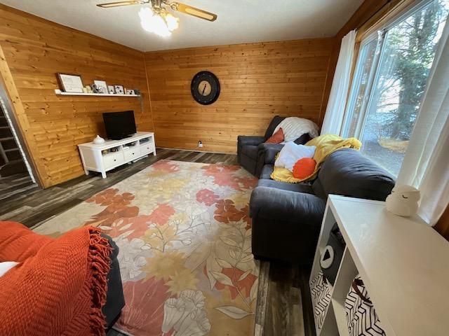 living area featuring wood finished floors, a ceiling fan, and wood walls