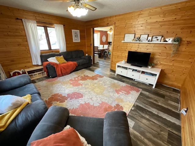 living area with wood finished floors, a ceiling fan, and wood walls