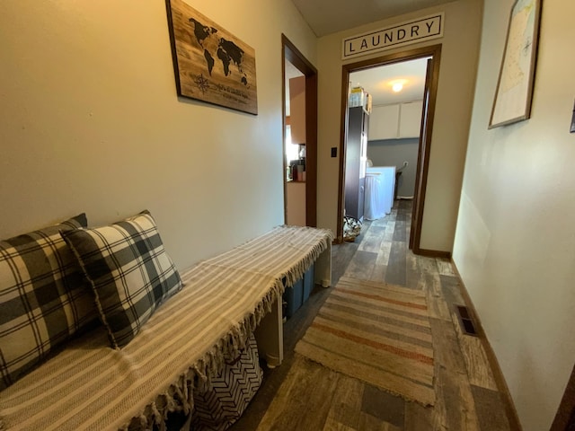 hall with dark wood finished floors, visible vents, and baseboards