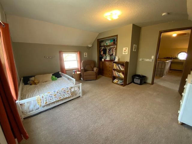 bedroom featuring a closet, a textured ceiling, carpet, and lofted ceiling