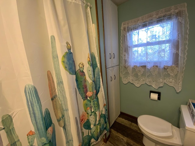 bathroom with curtained shower, toilet, and wood finished floors