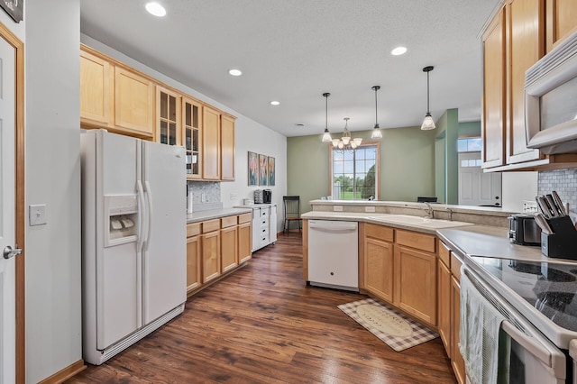 kitchen featuring a sink, white appliances, a peninsula, glass insert cabinets, and a chandelier